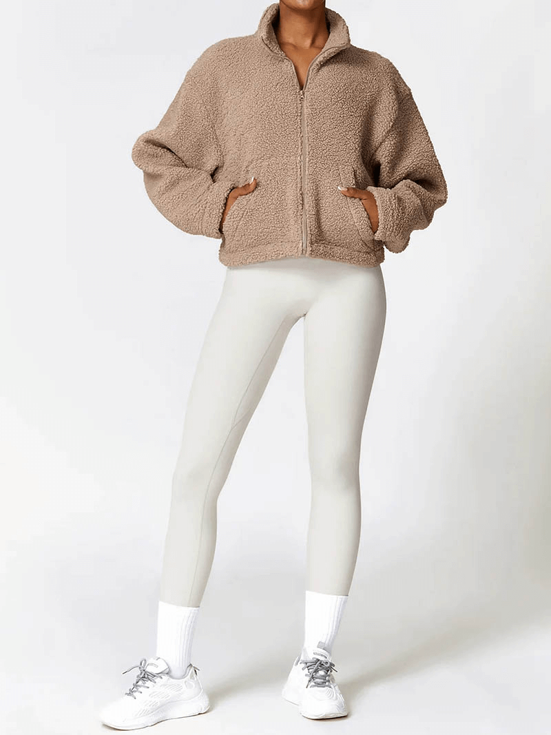 Woman wearing a thick fleece jacket with zipper and white leggings, showcasing winter fashion.